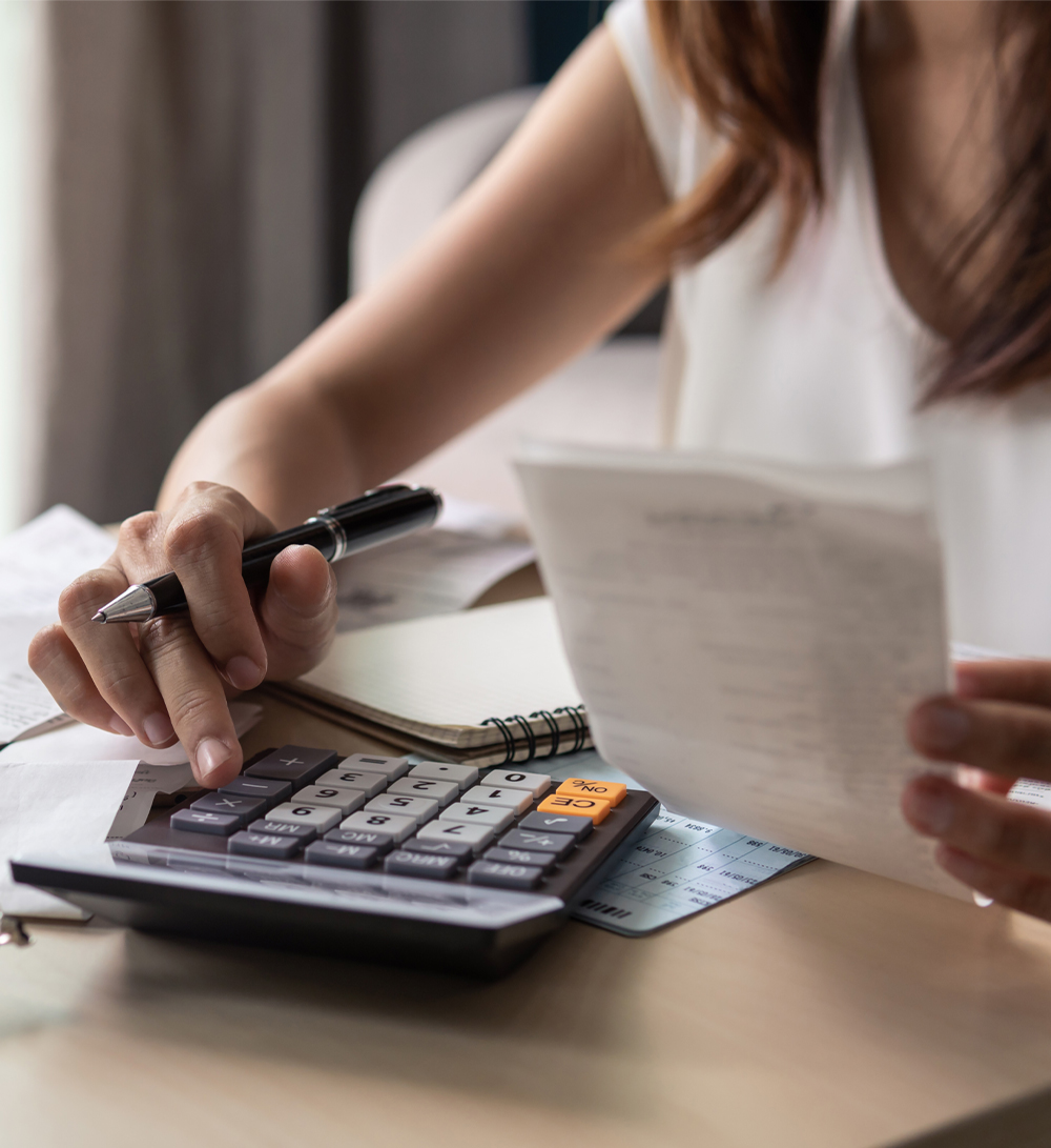 Woman uses calculator while looking at bills