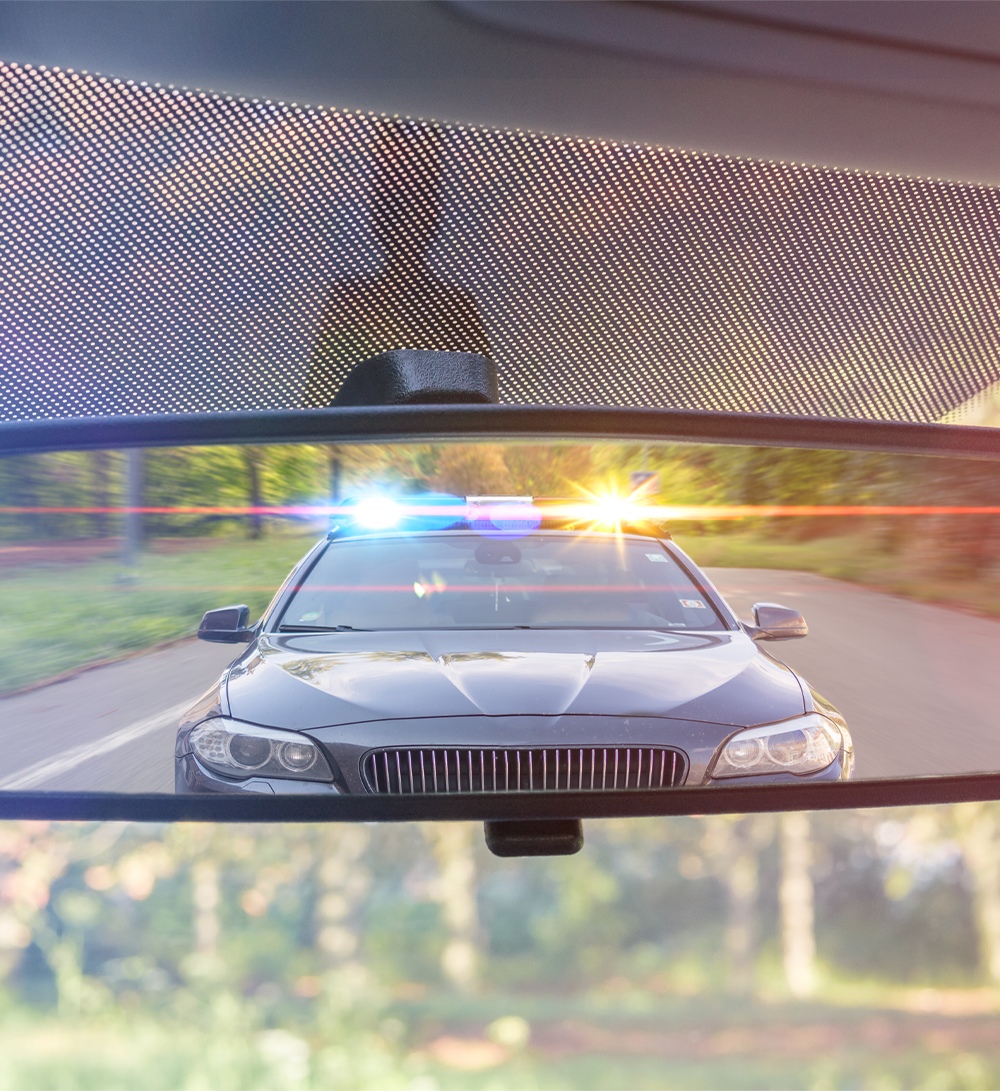 Police car with lights as seen in a rearview mirror