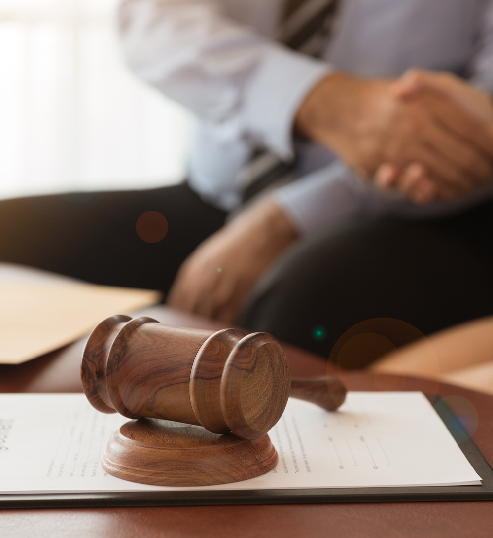 Two people shake hands with a judge's gavel in the foreground