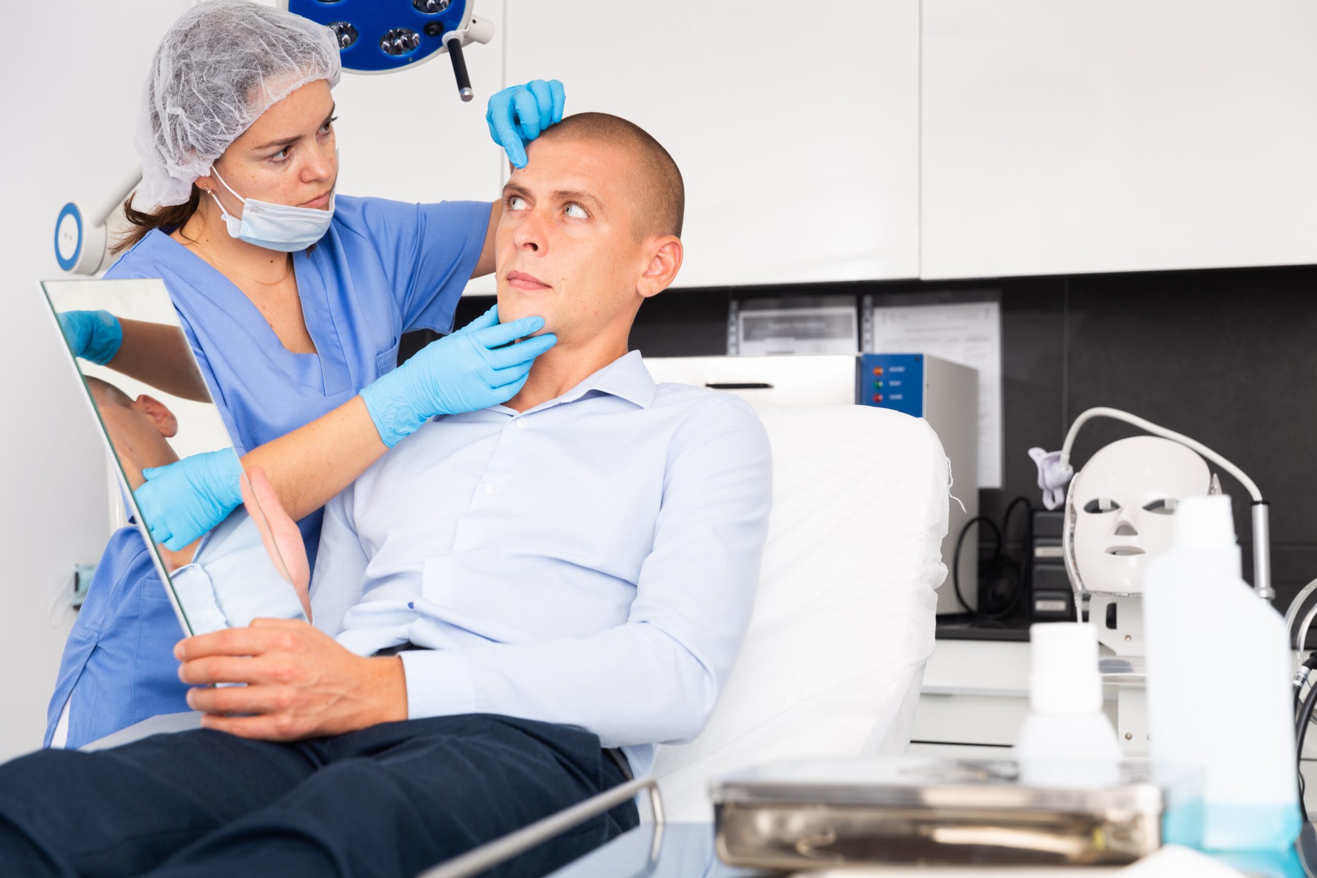 Doctor examining a patient’s face while the patient looks in a mirror, representing an independent medical evaluation (IME) in Niagara County