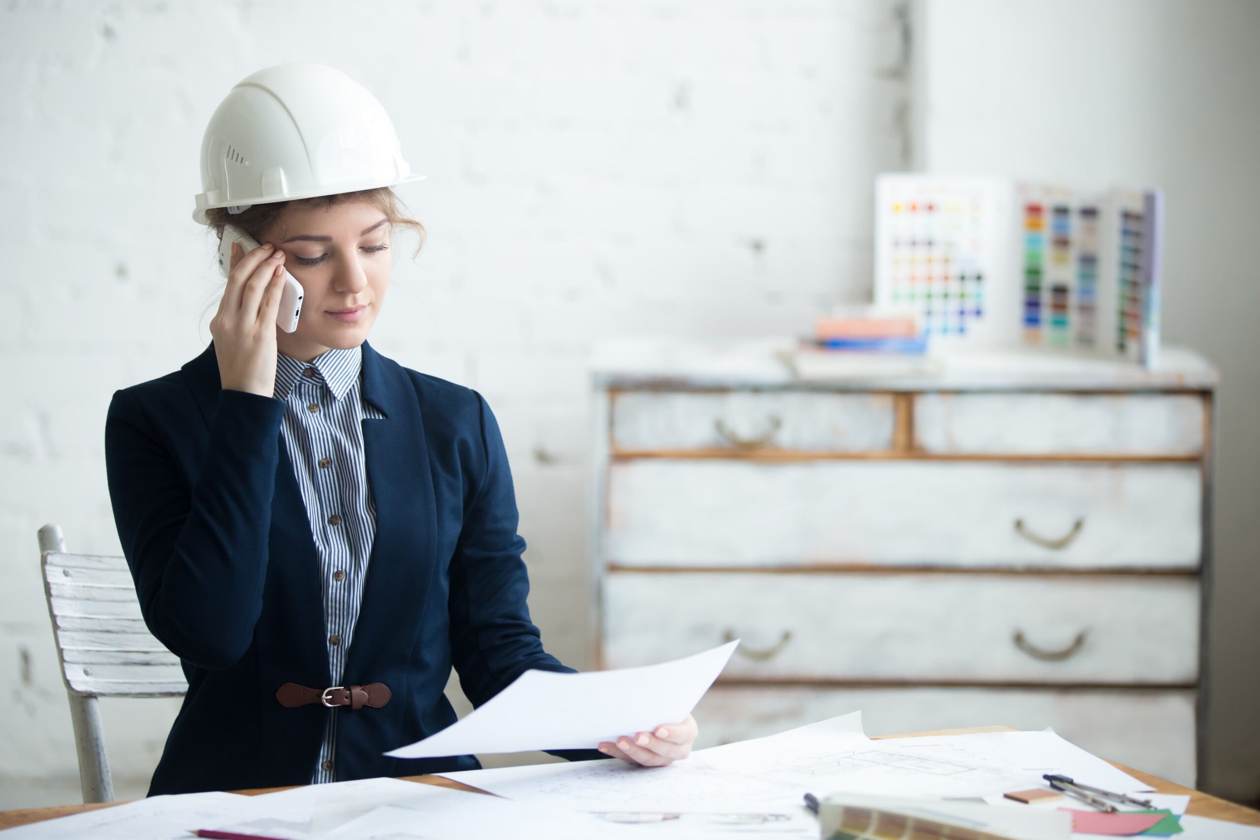 Professional wearing a hard hat reviewing documents and speaking on the phone before a workers’ compensation hearing.