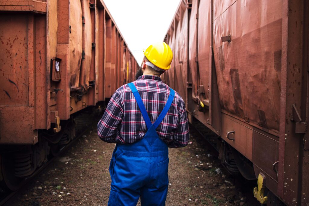 Rail yard worker walking between train cars, representing workplace injury claims and FELA cases in a rail yard setting.
