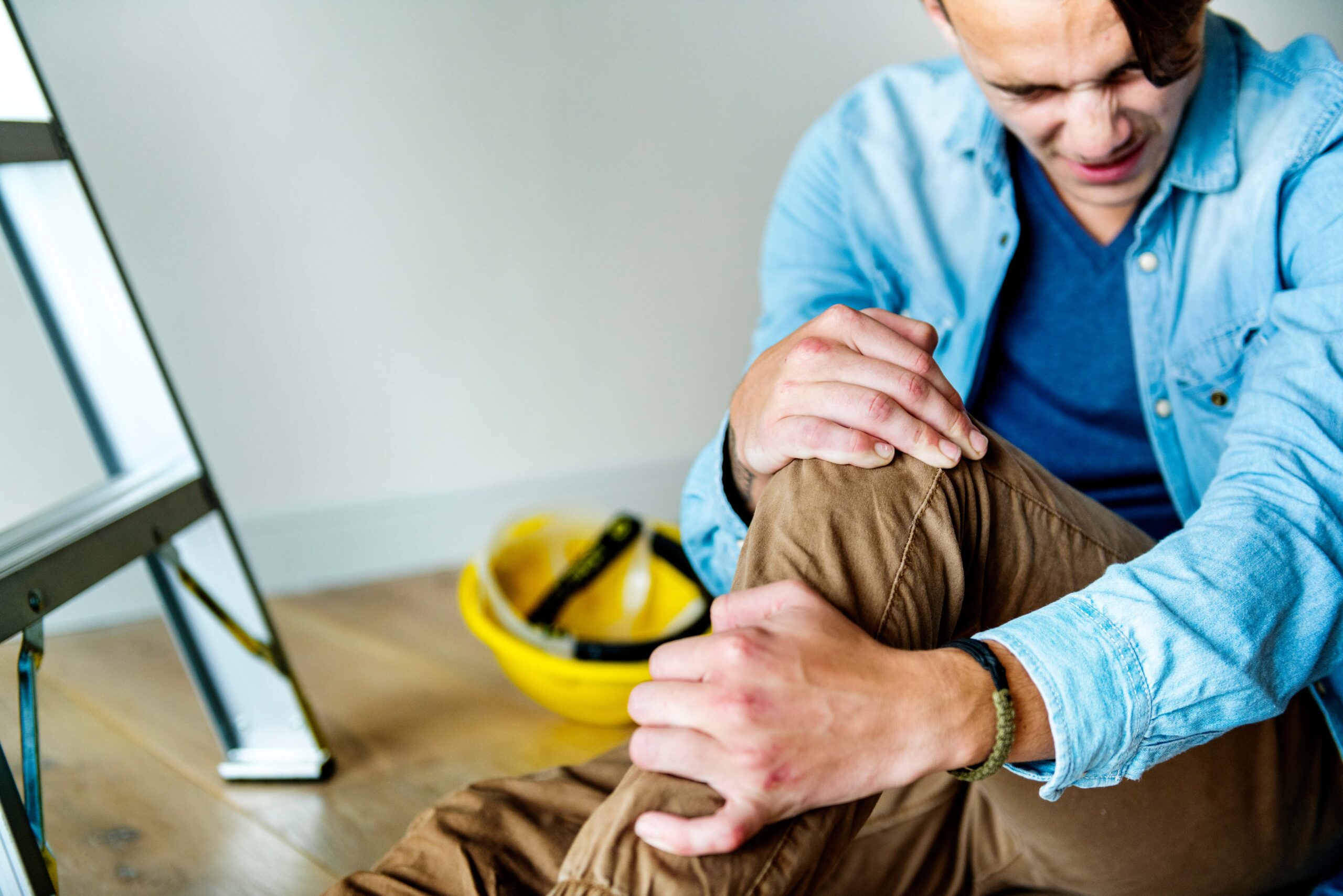 Injured worker holding knee after a workplace accident, representing a serious injury and Section 32 workers’ compensation settlement.