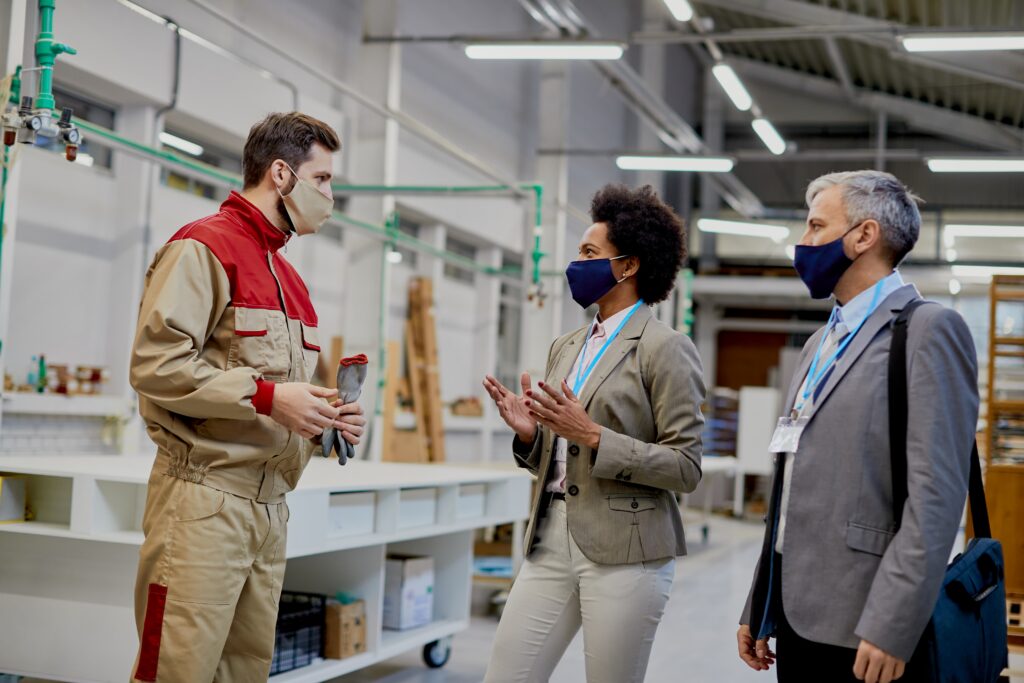 Manufacturing worker speaking with managers about occupational disease risks in a factory setting.